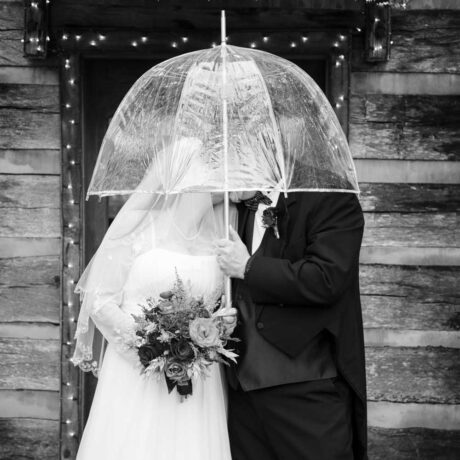 Happy couple on their wedding day holding an umbrella outdoors